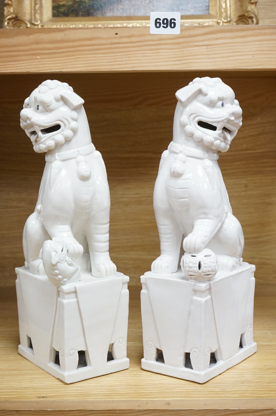 A pair of Chinese white glazed lion dogs, stamped ‘Wai Ming Hong Kong’ to base, 30cm